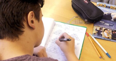 Ein Werkrealschüler schreibt in sein Arbeitsheft